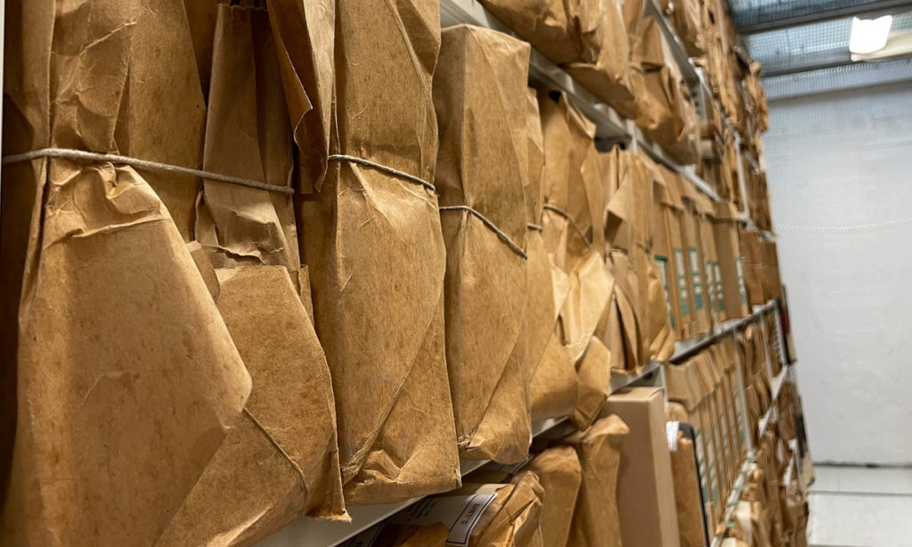 arkivhyller med esker og innpakket papir